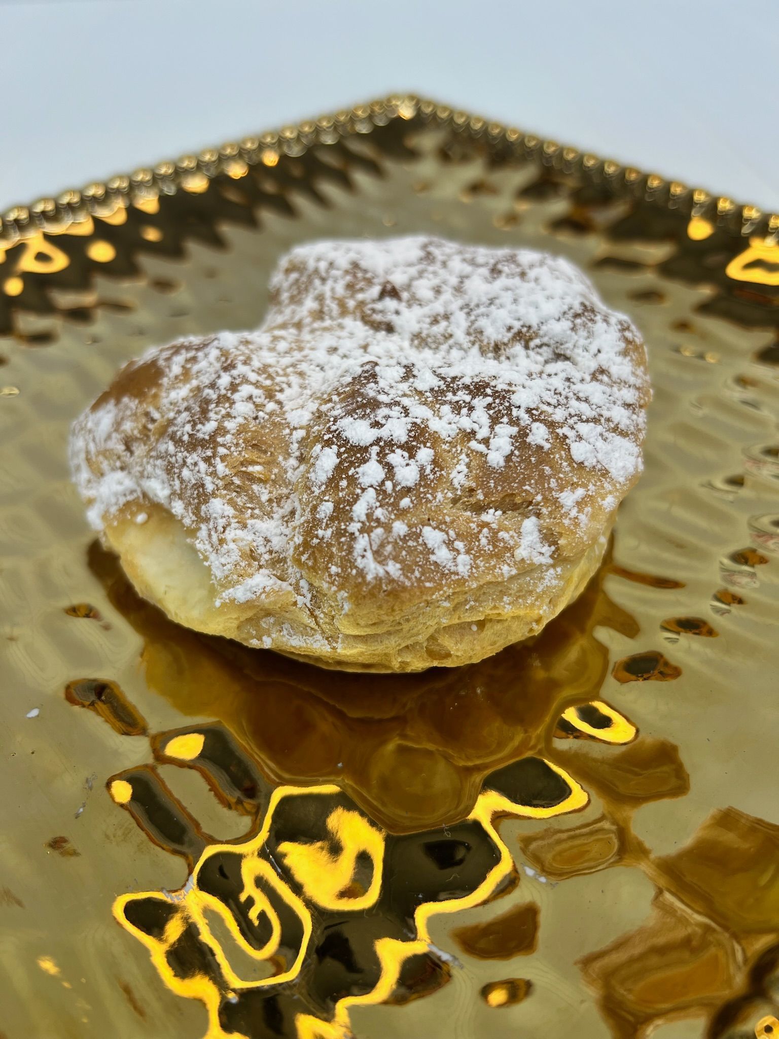 Pastry dusted with powdered sugar on a decorative gold plate.