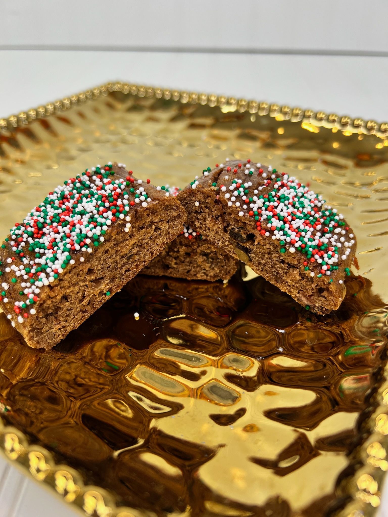 Two chocolate biscotti with sprinkles on a gold, textured platter.