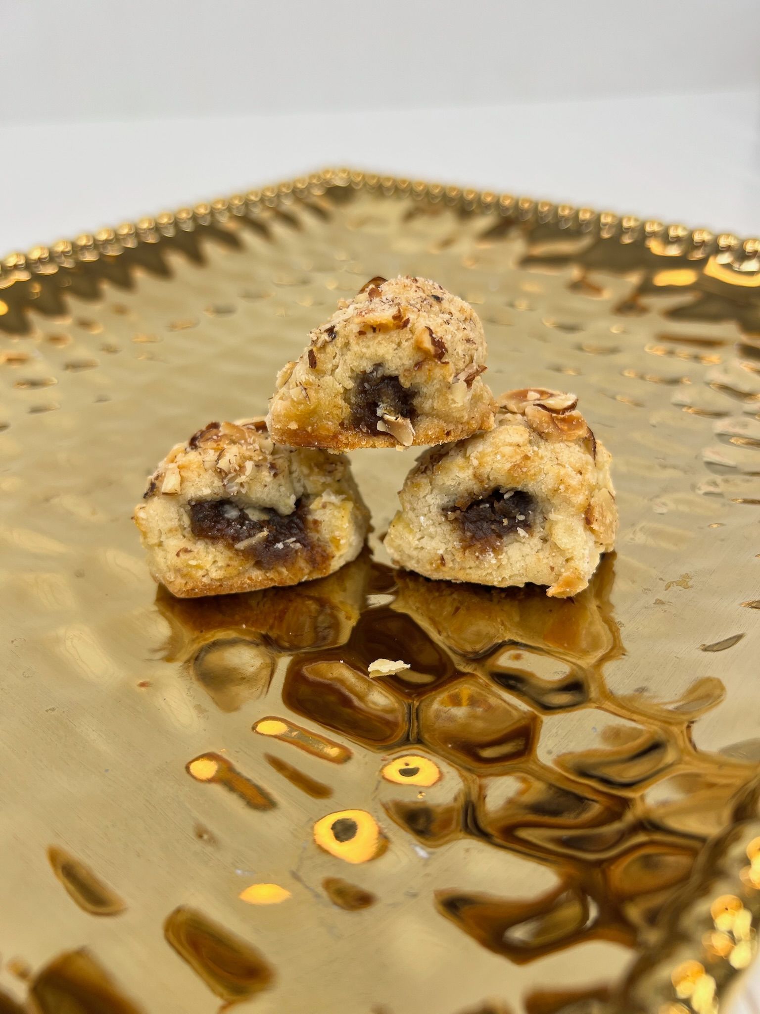 Three date-filled cookies stacked on a gold, textured serving tray.