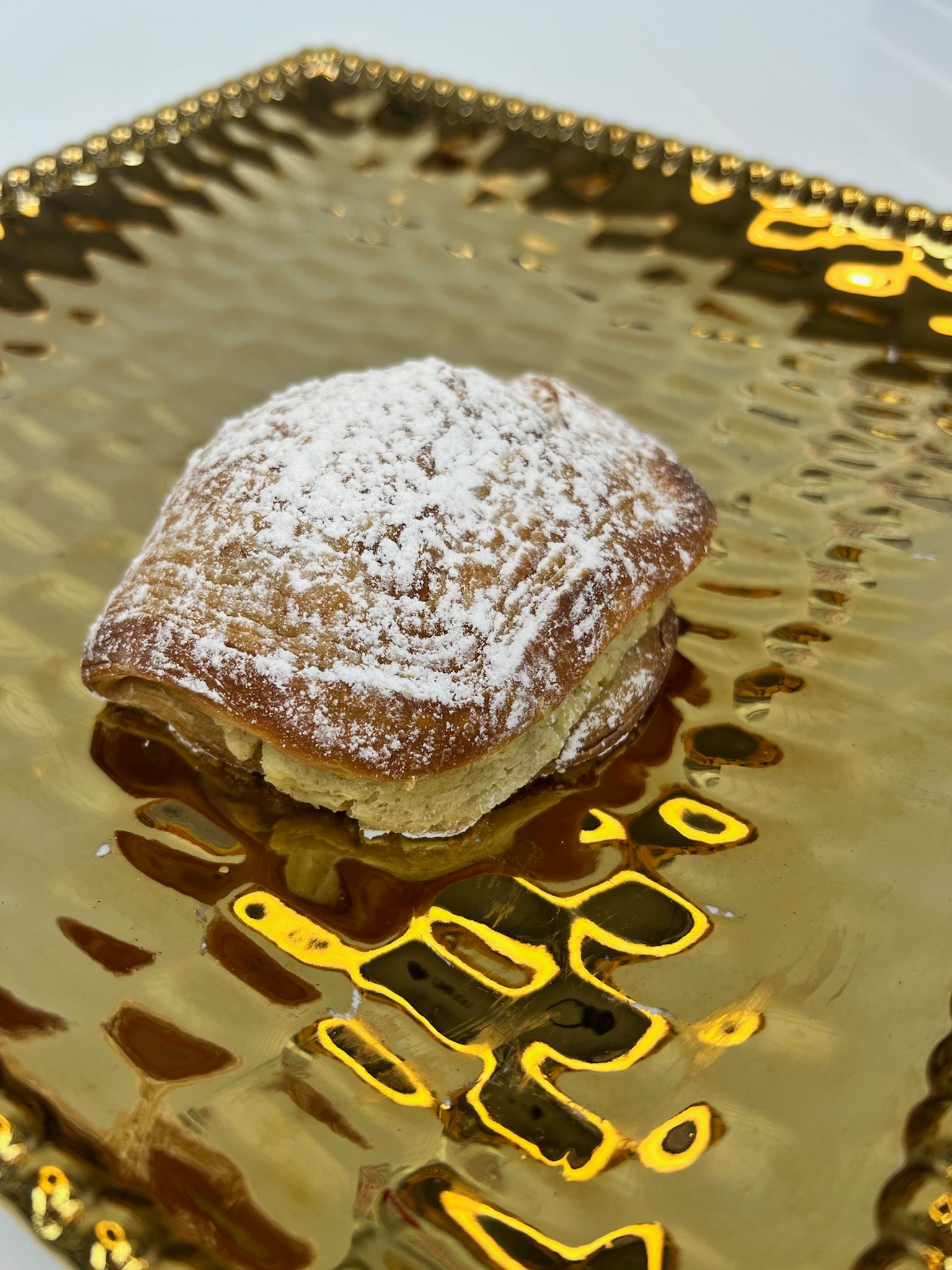 Pastry dusted with powdered sugar on a gold, textured serving tray.