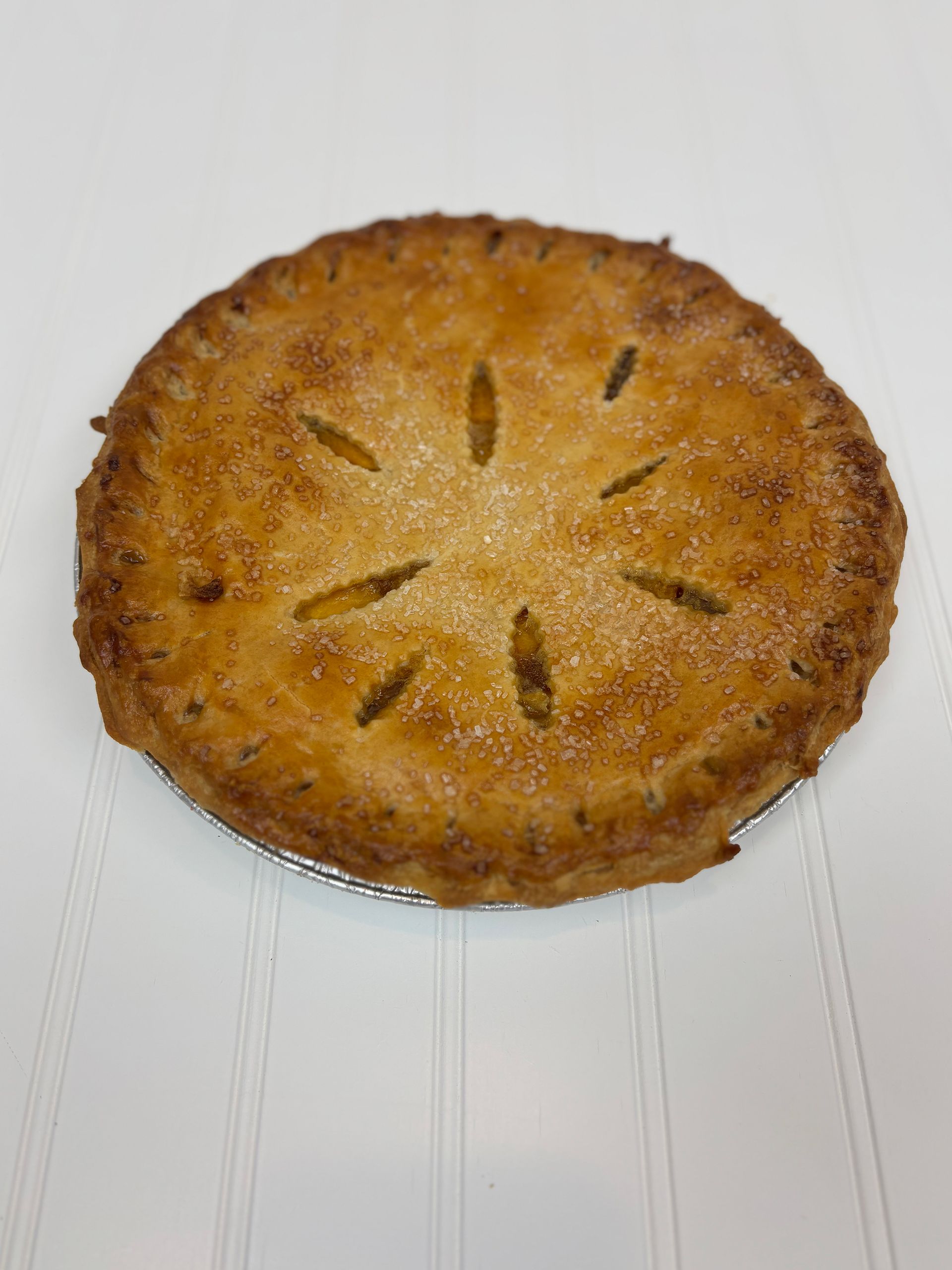 Golden-brown, baked pie with star-shaped slits, on a white surface.
