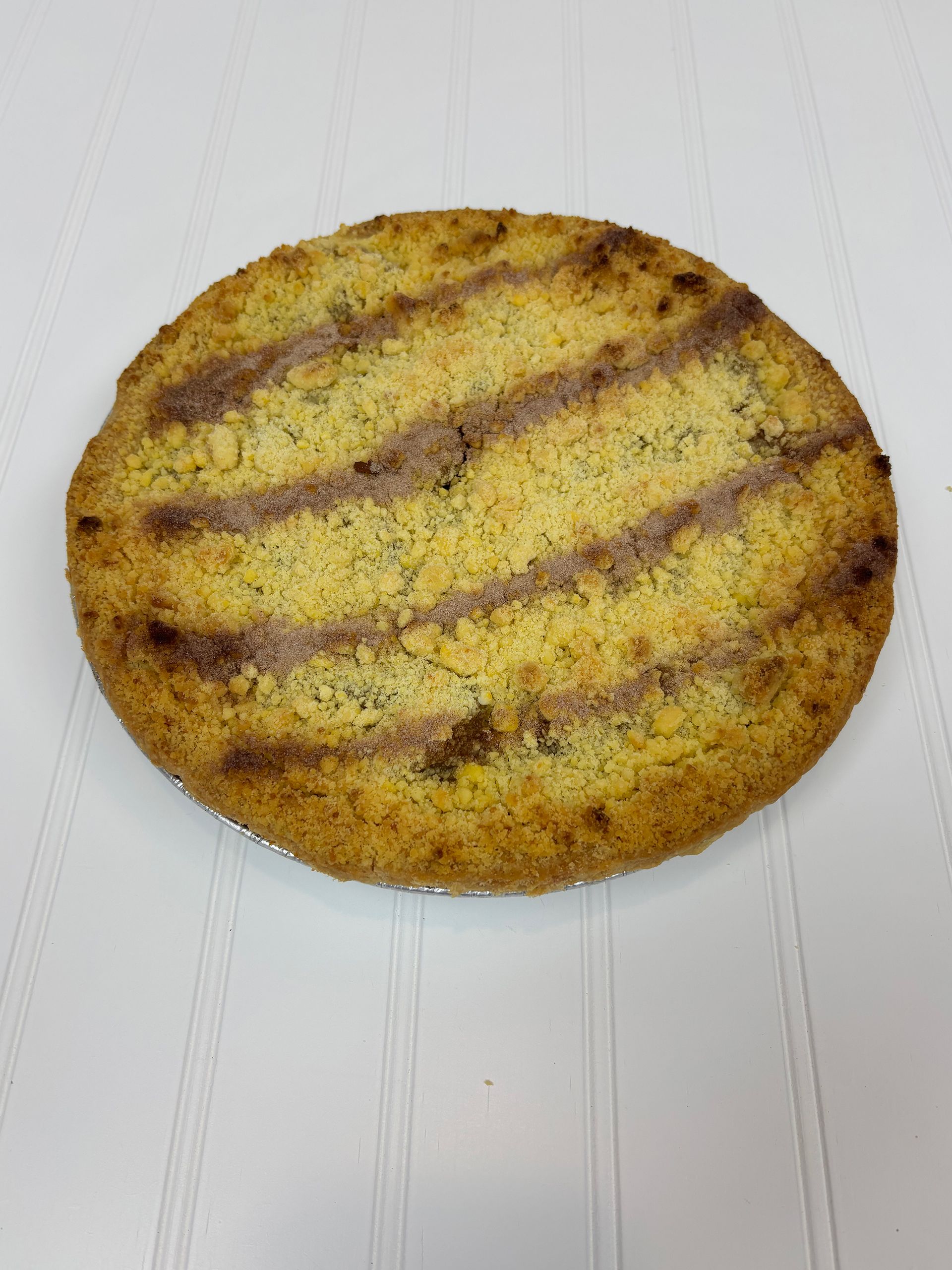 Round, golden-brown baked item with grilled stripes; placed on a white surface.