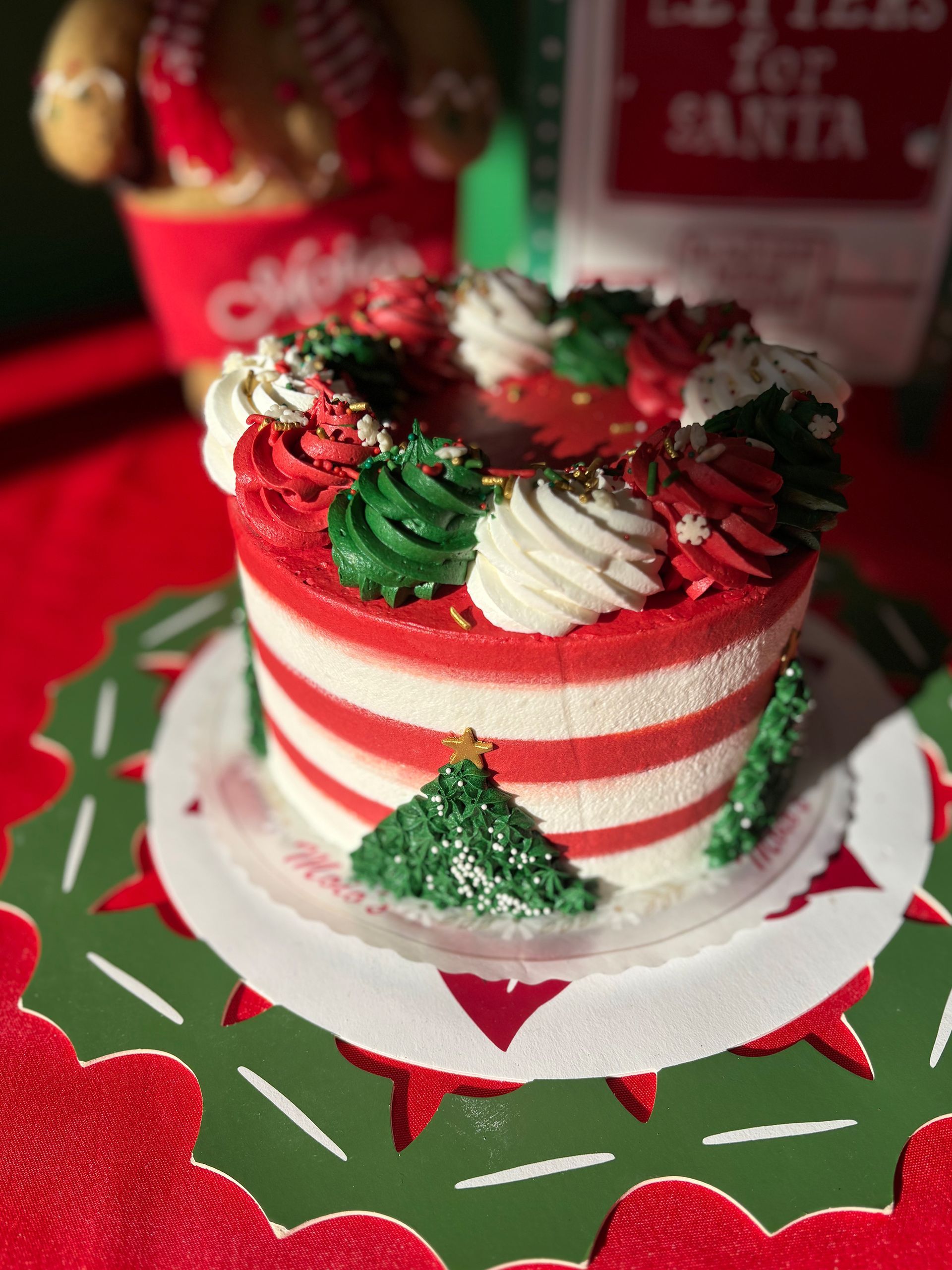 Christmas cake with red and white stripes, decorated with frosting, on a green and red table setting.