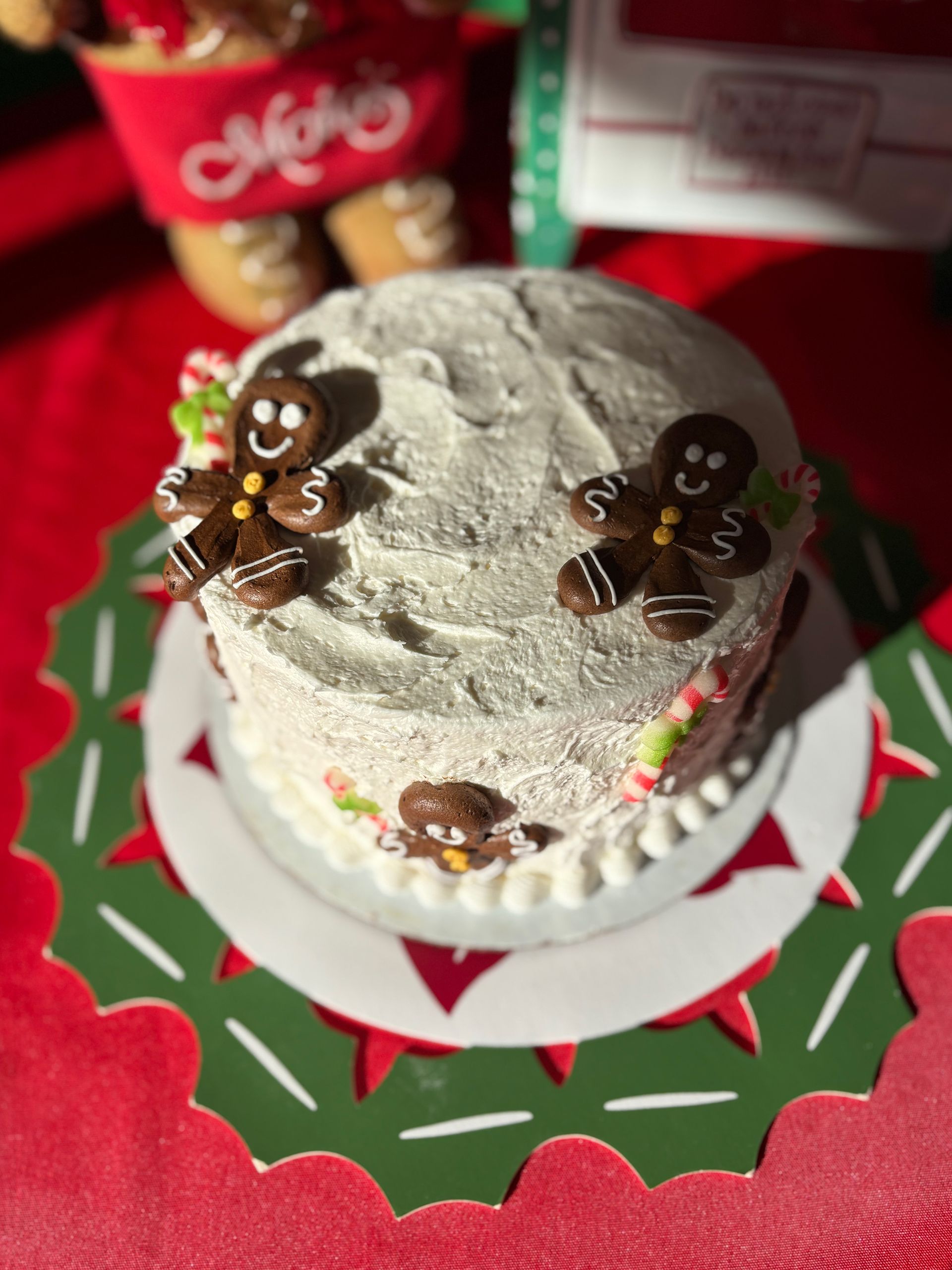 Christmas cake decorated with gingerbread men on a green and white platter over a red surface.