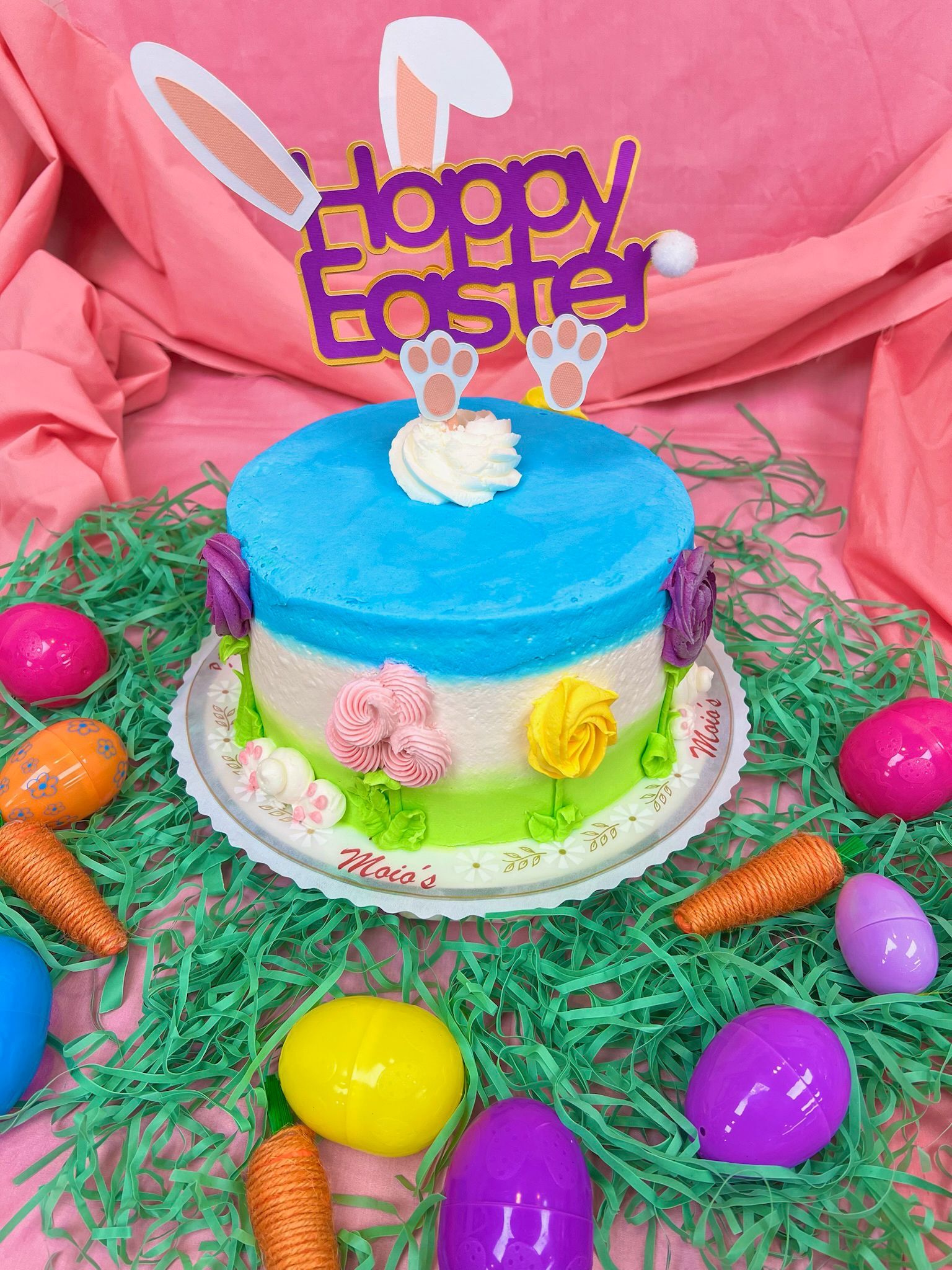 Easter cake with bunny ears, decorated with eggs and carrots.