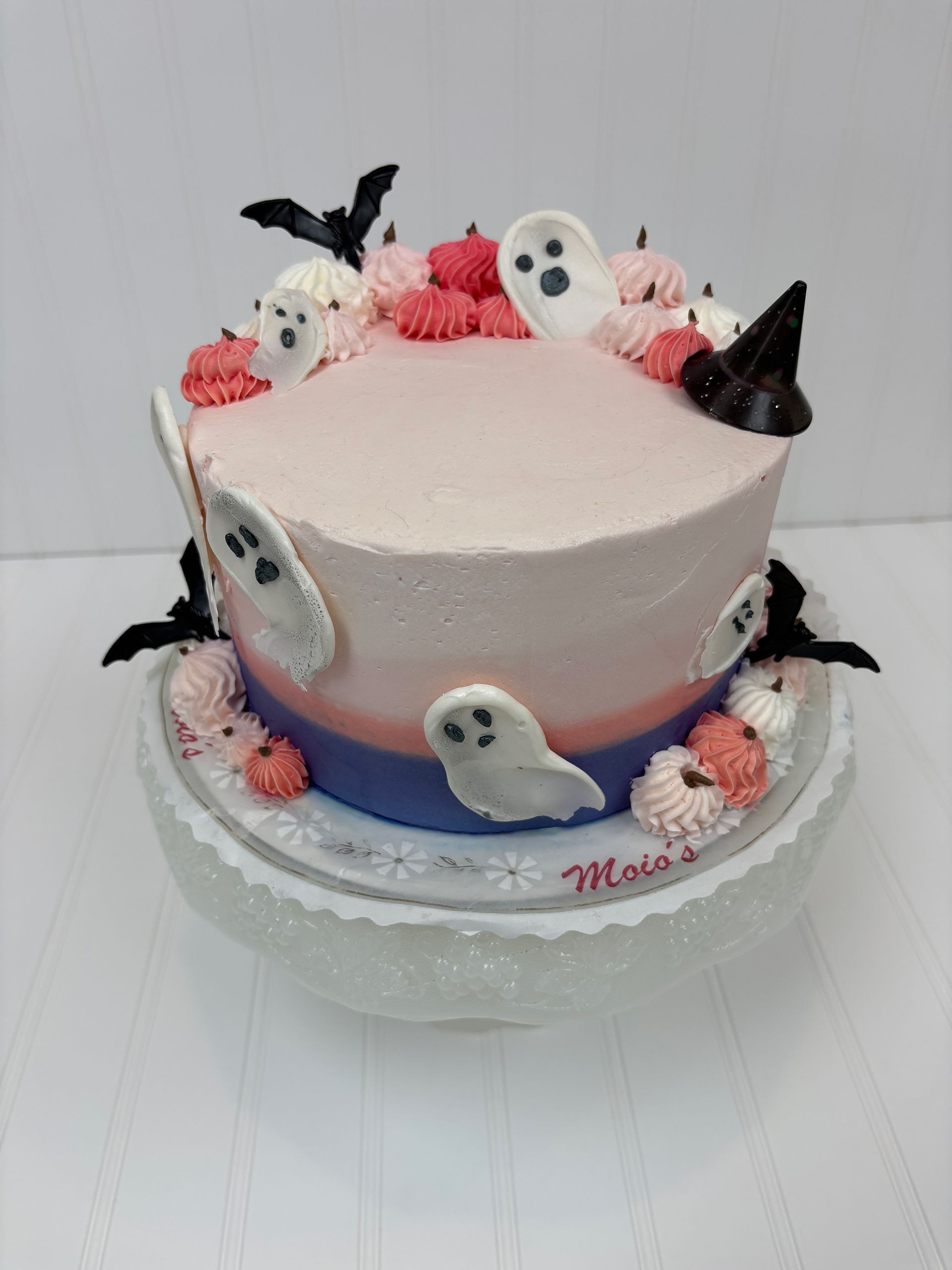 Halloween cake with ghosts, bats, and pumpkins; pink and blue ombre frosting.