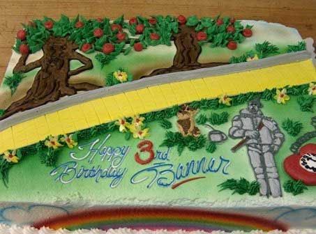 Birthday cake with Wizard of Oz theme: Yellow brick road, trees, Tin Man, rainbow.