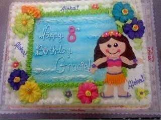 Hawaiian-themed birthday cake with a girl figure, flowers, and the words