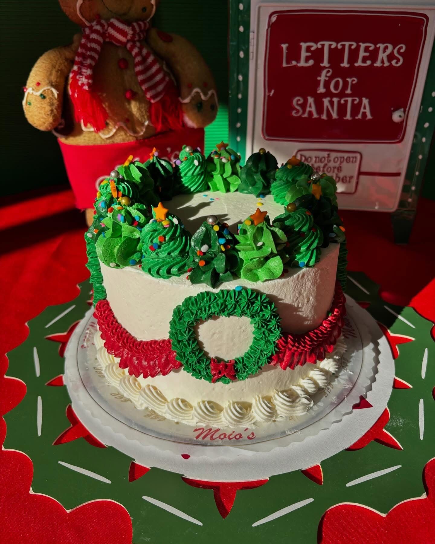 Christmas cake decorated with green frosting wreaths and trees