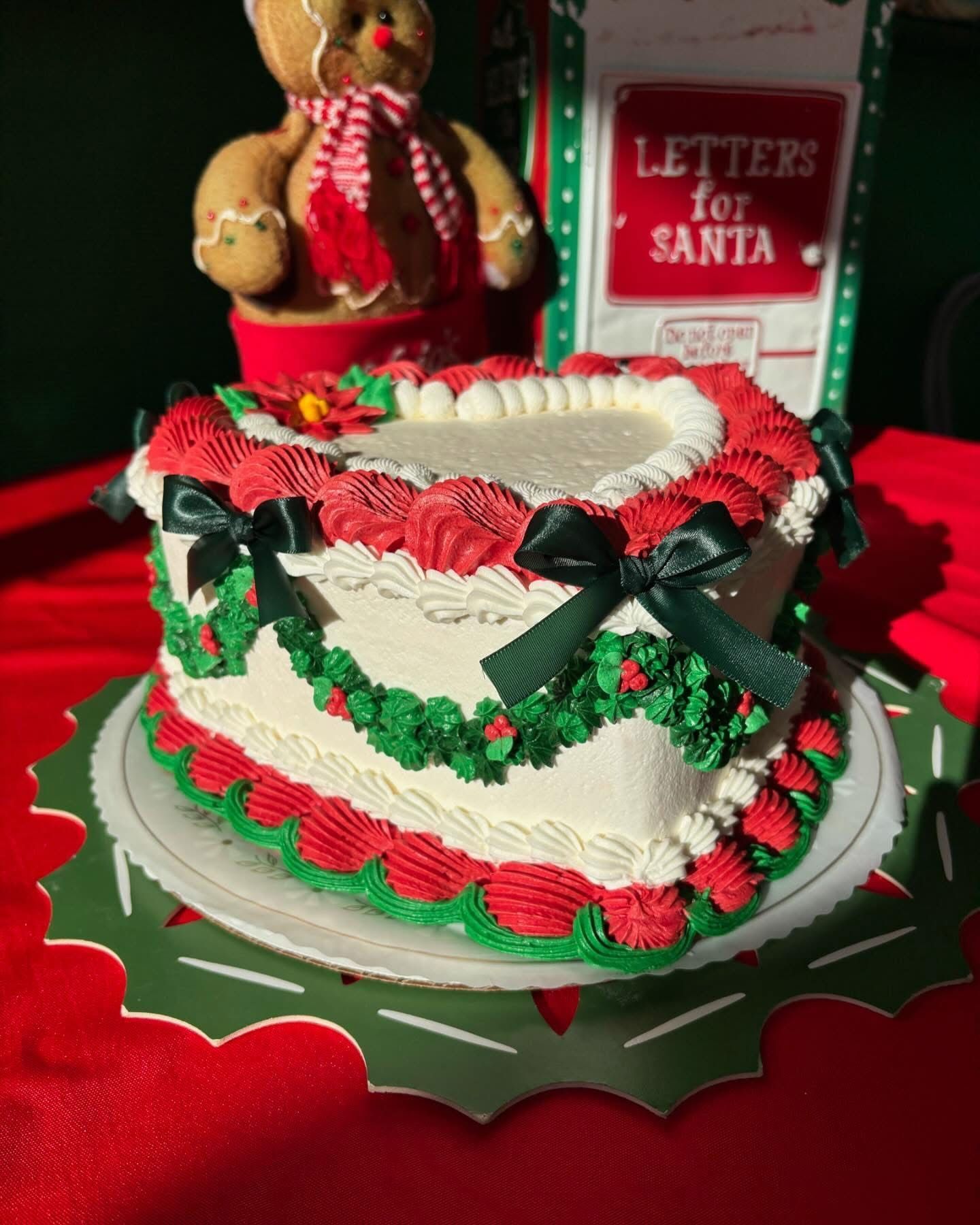 Heart-shaped Christmas cake decorated with red and green frosting, bows, and holly.