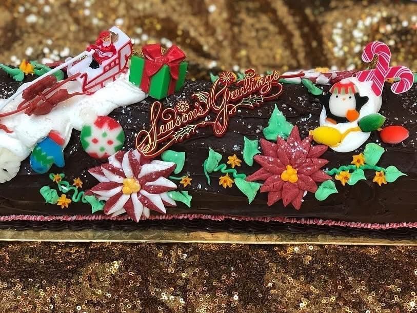 Chocolate Yule log cake decorated with Christmas candies and a penguin.