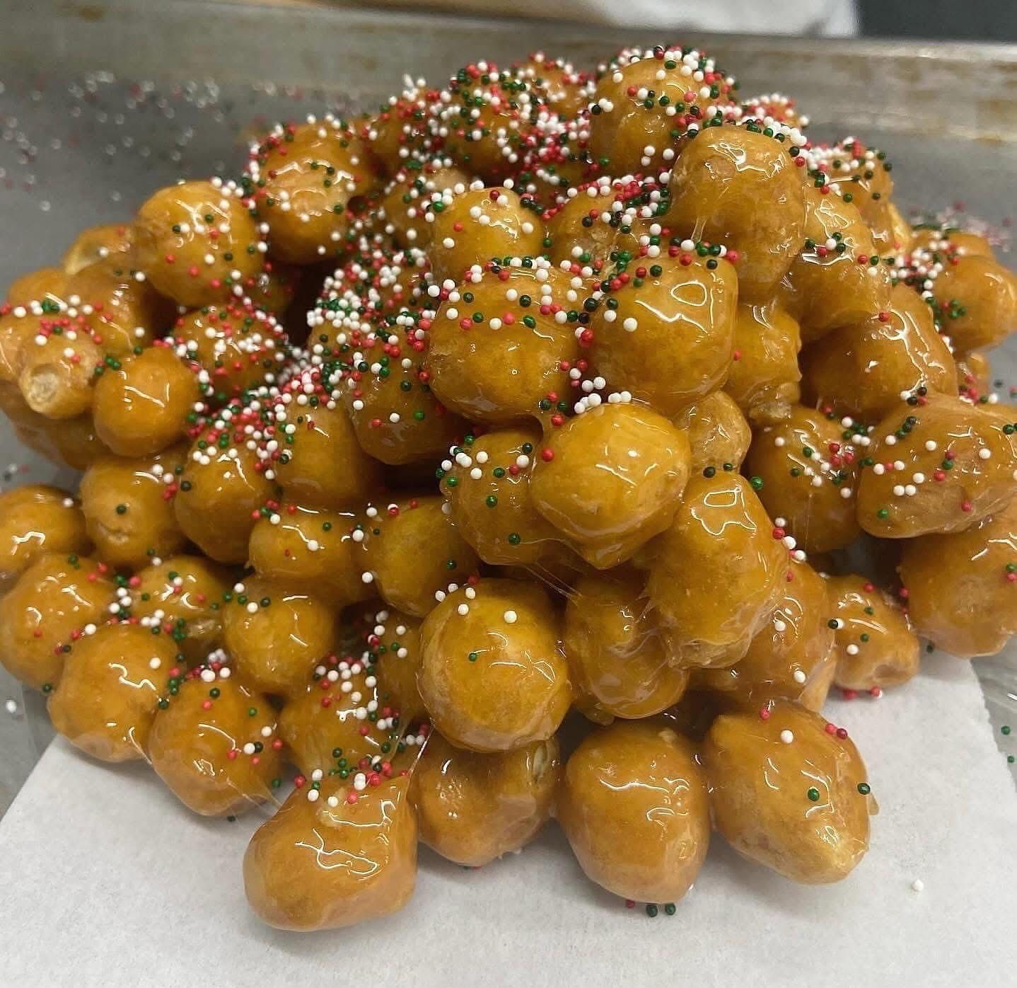 Golden fried zeppole balls drizzled with honey, topped with sprinkles.