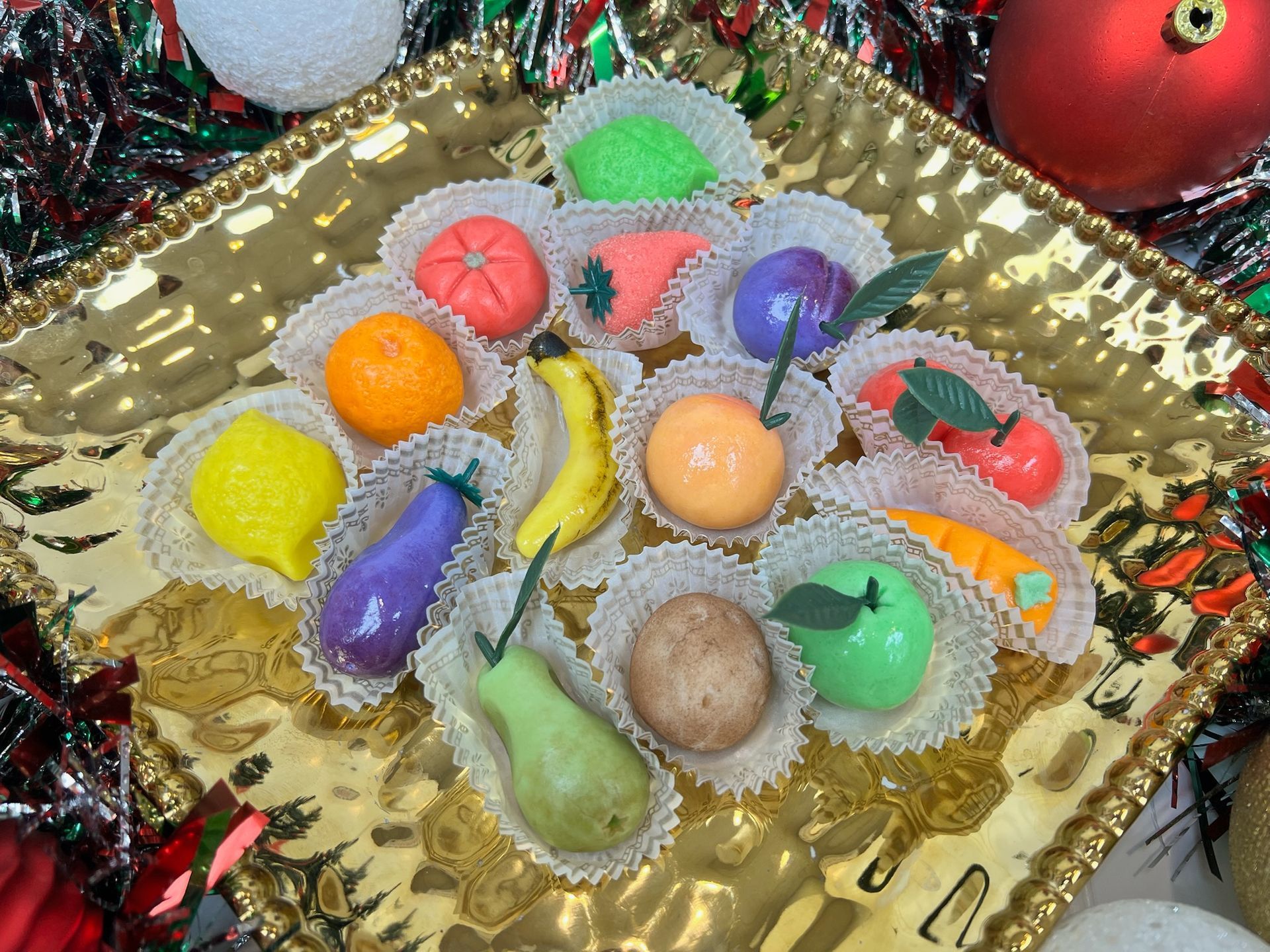 Marzipan fruits in a gold dish, decorated for the holidays.