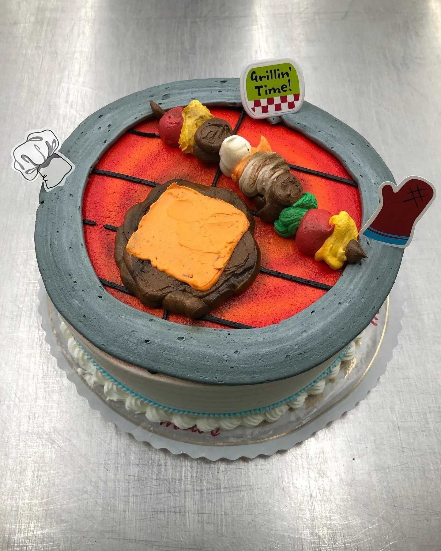 Cake decorated as a grill with a burger and kebab, with a chef's hat and oven mitt.