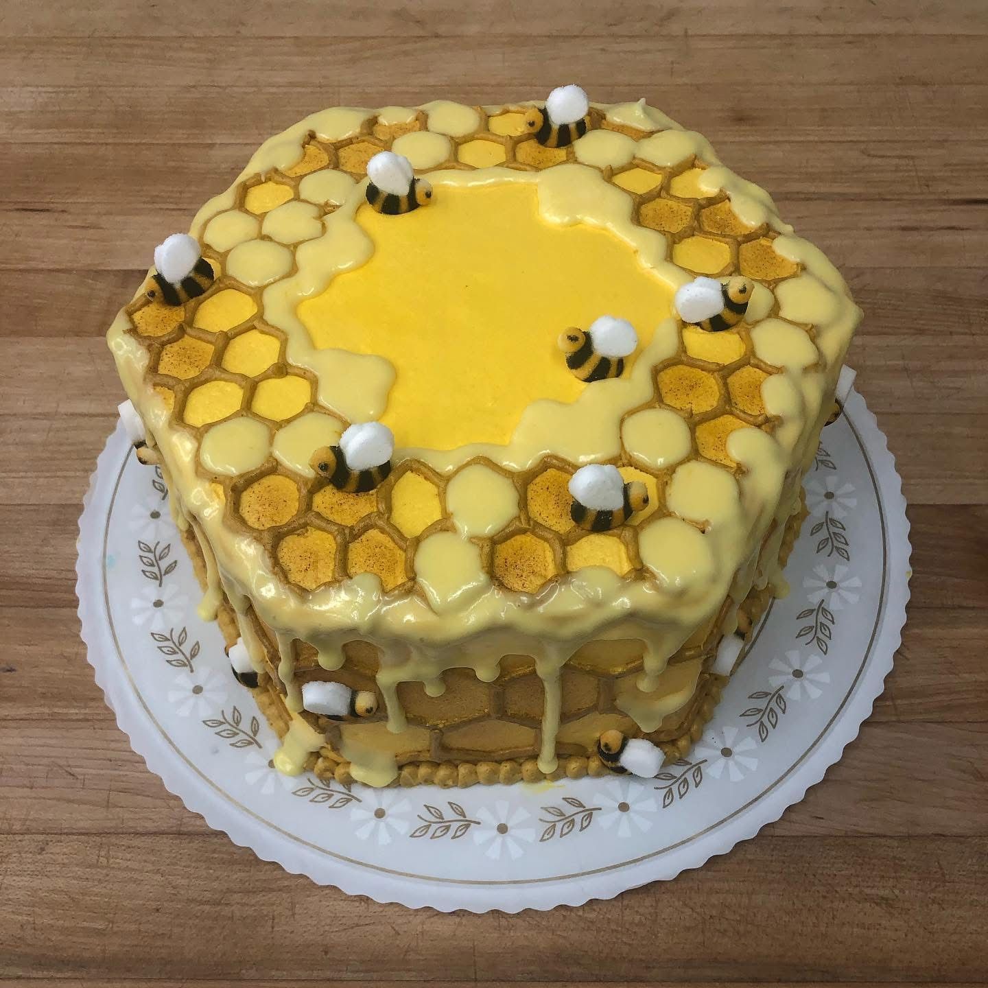 Honeycomb cake decorated with yellow frosting, honeycomb cells, and fondant bees.