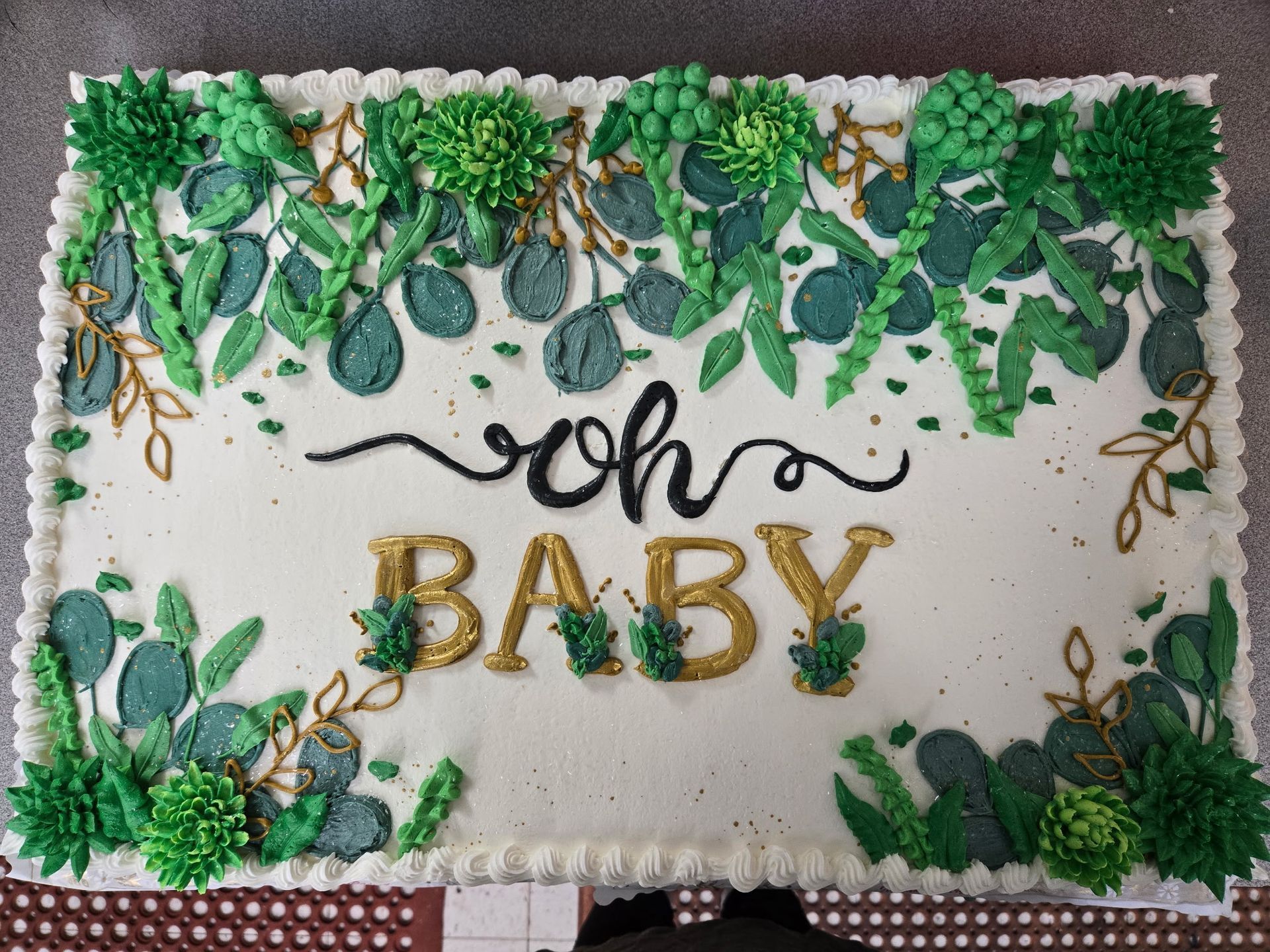Rectangular baby shower cake with green floral frosting.