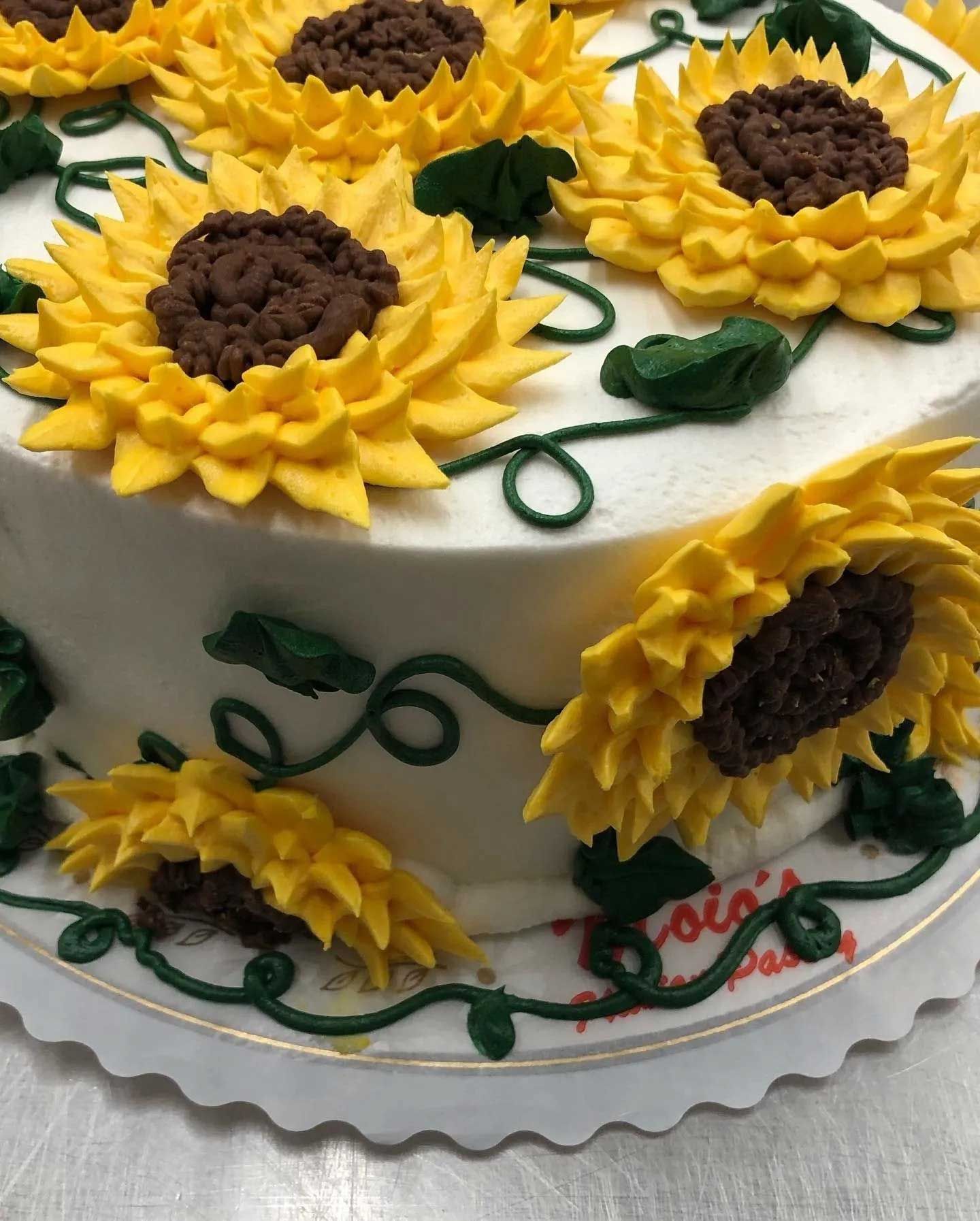 Cake decorated with yellow sunflower frosting and green vines.