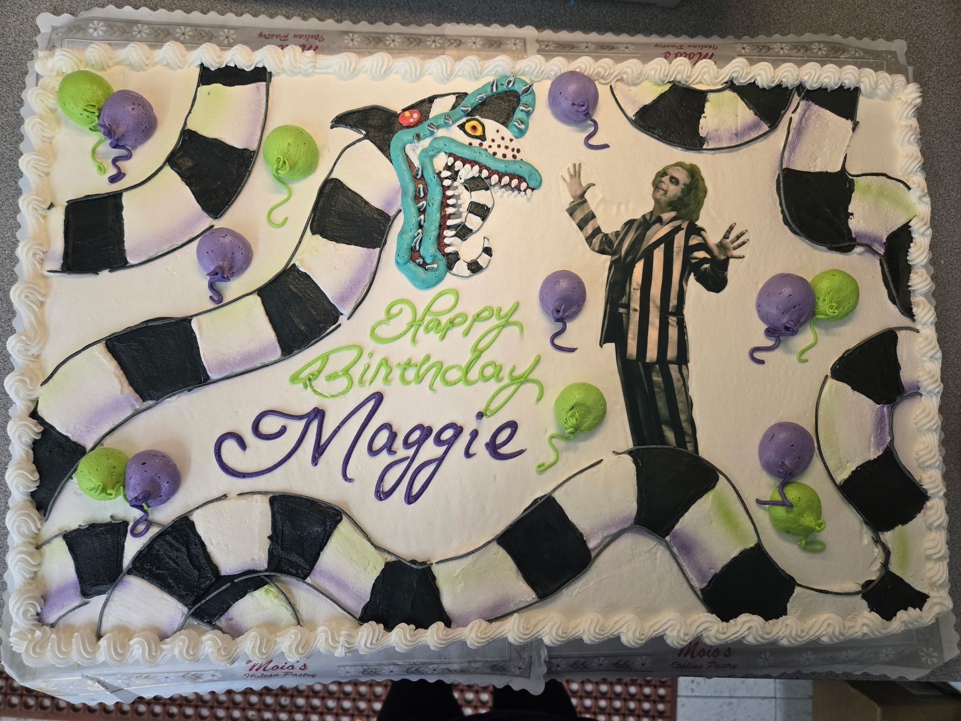 Beetlejuice birthday cake with green, purple balloons, and a black and white snake design.