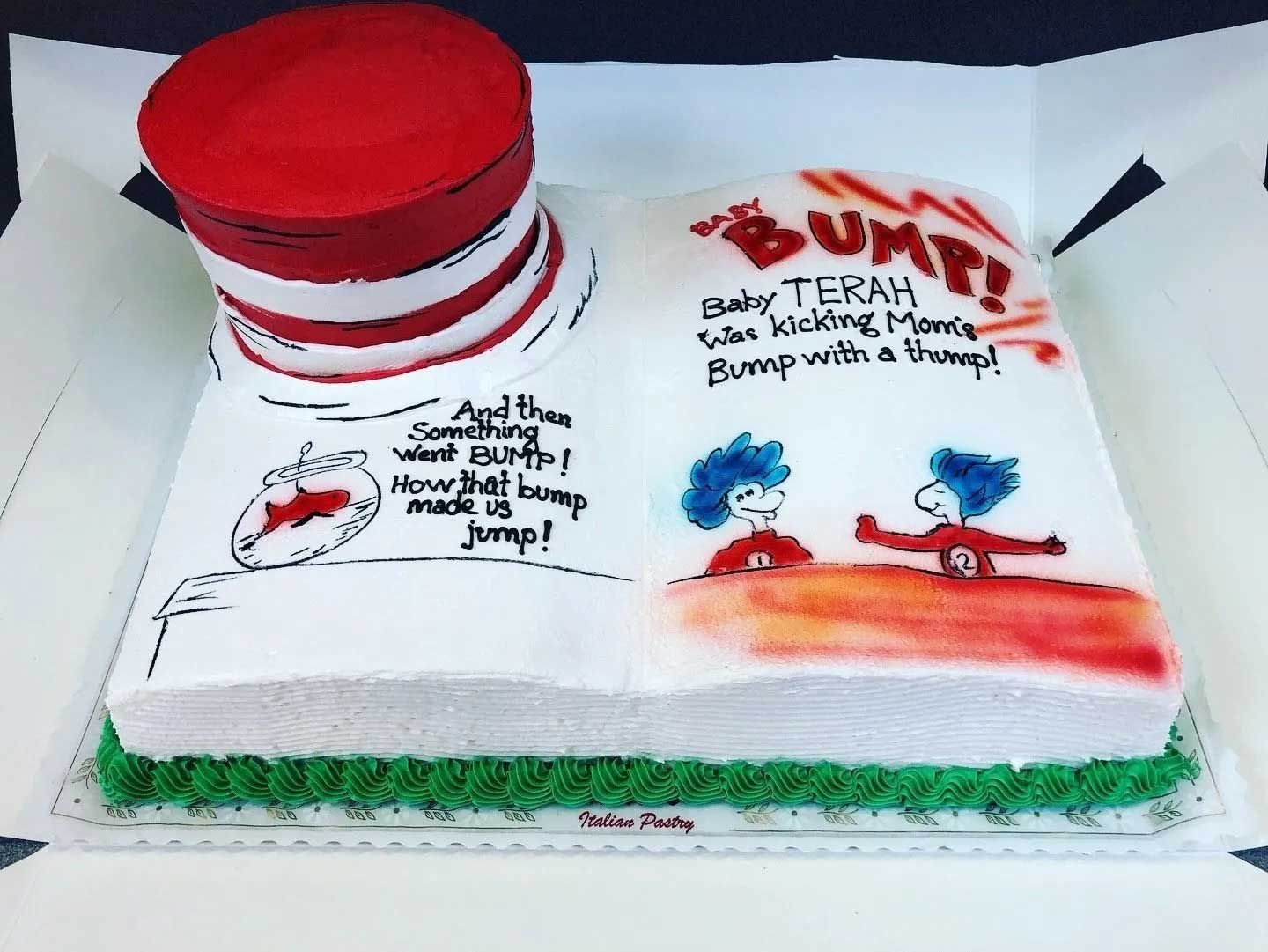 Cat in the Hat themed baby shower cake. Open book shape with red hat, cartoon illustrations, text.