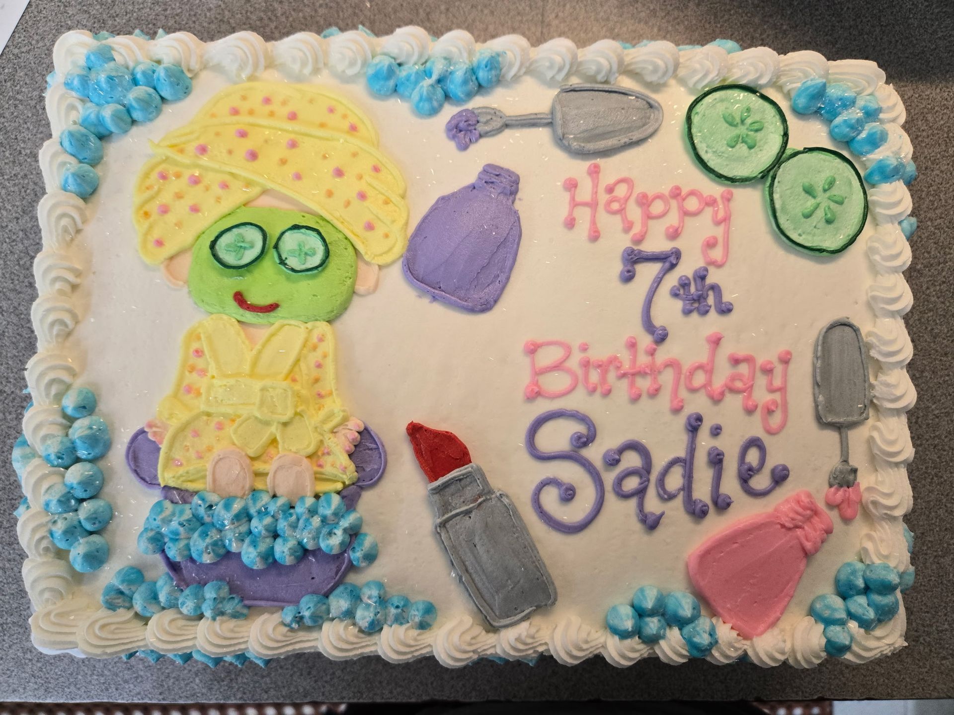 Cake decorated as a spa scene: a person with a towel and cucumber slices, spa items.
