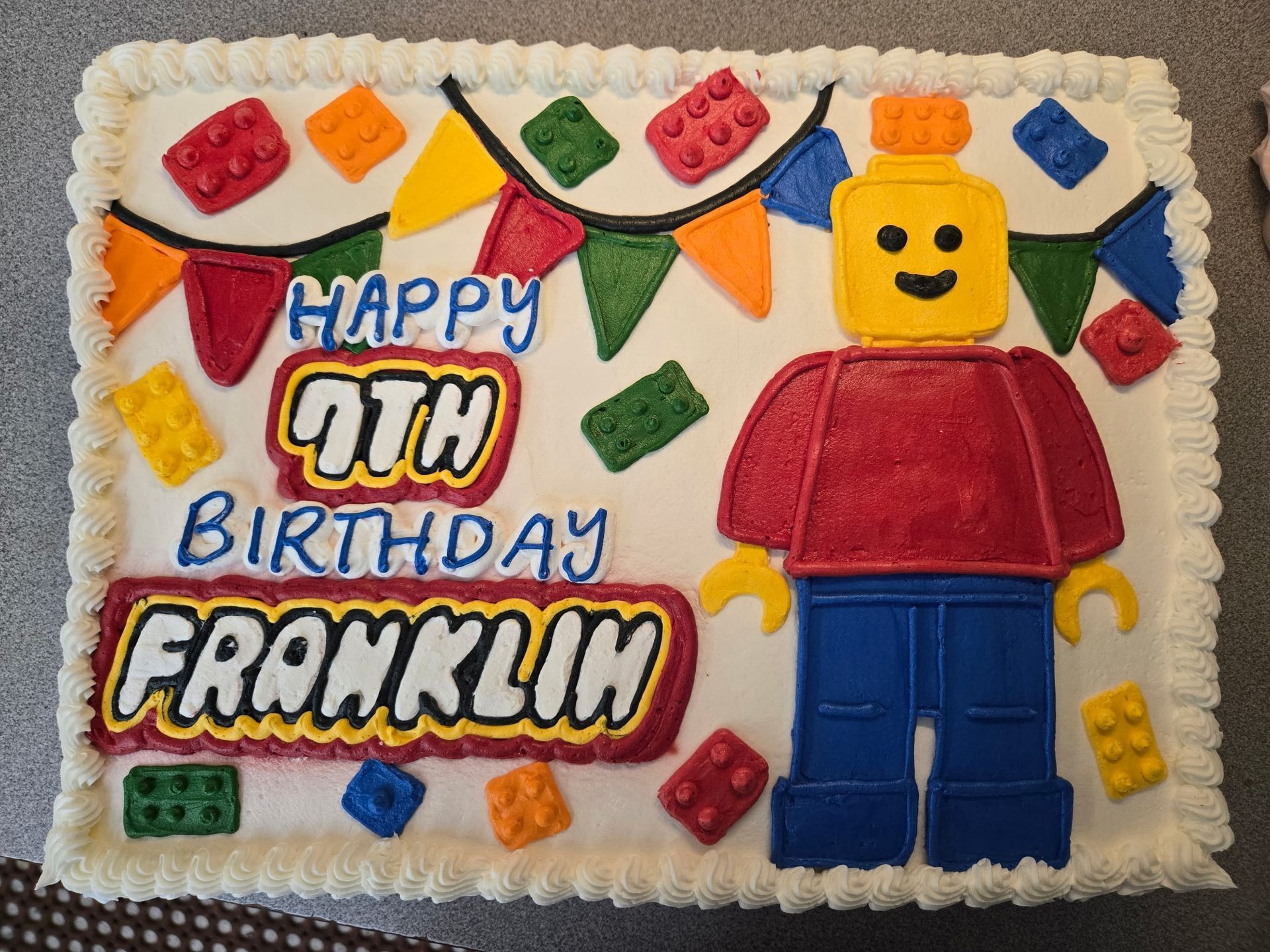 Lego-themed cake with Happy 7th Birthday Franklin text and Lego figure, decorated with colorful Lego bricks and bunting.