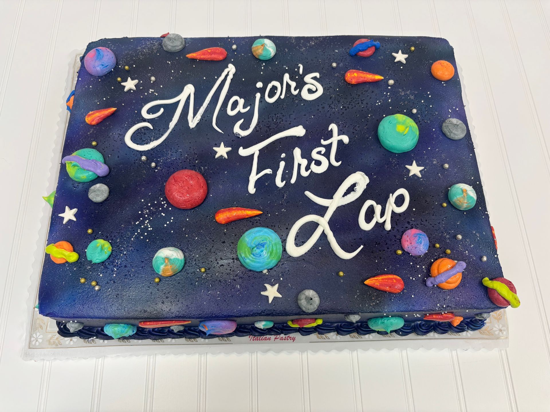 Galaxy-themed cake with planets and stars; text reads Major's First Lap.