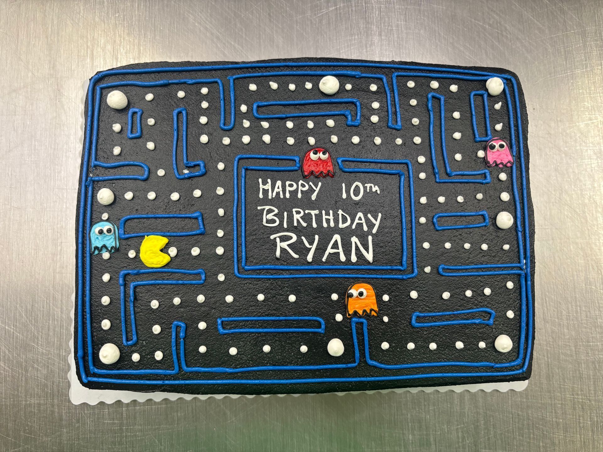 Pac-Man birthday cake with a maze design, decorated with edible ghosts and Pac-Man.