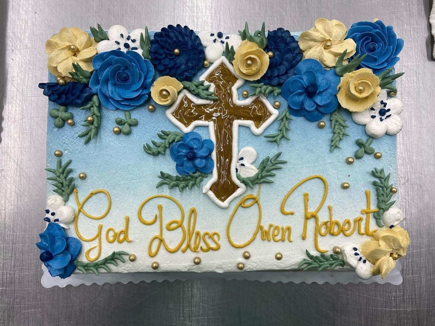 Cake decorated with blue and gold flower and a cross.