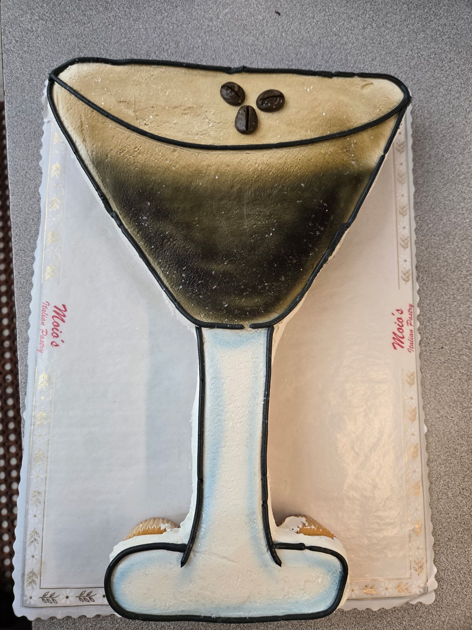 Martini-shaped cake with coffee beans, decorated with brown and tan frosting.