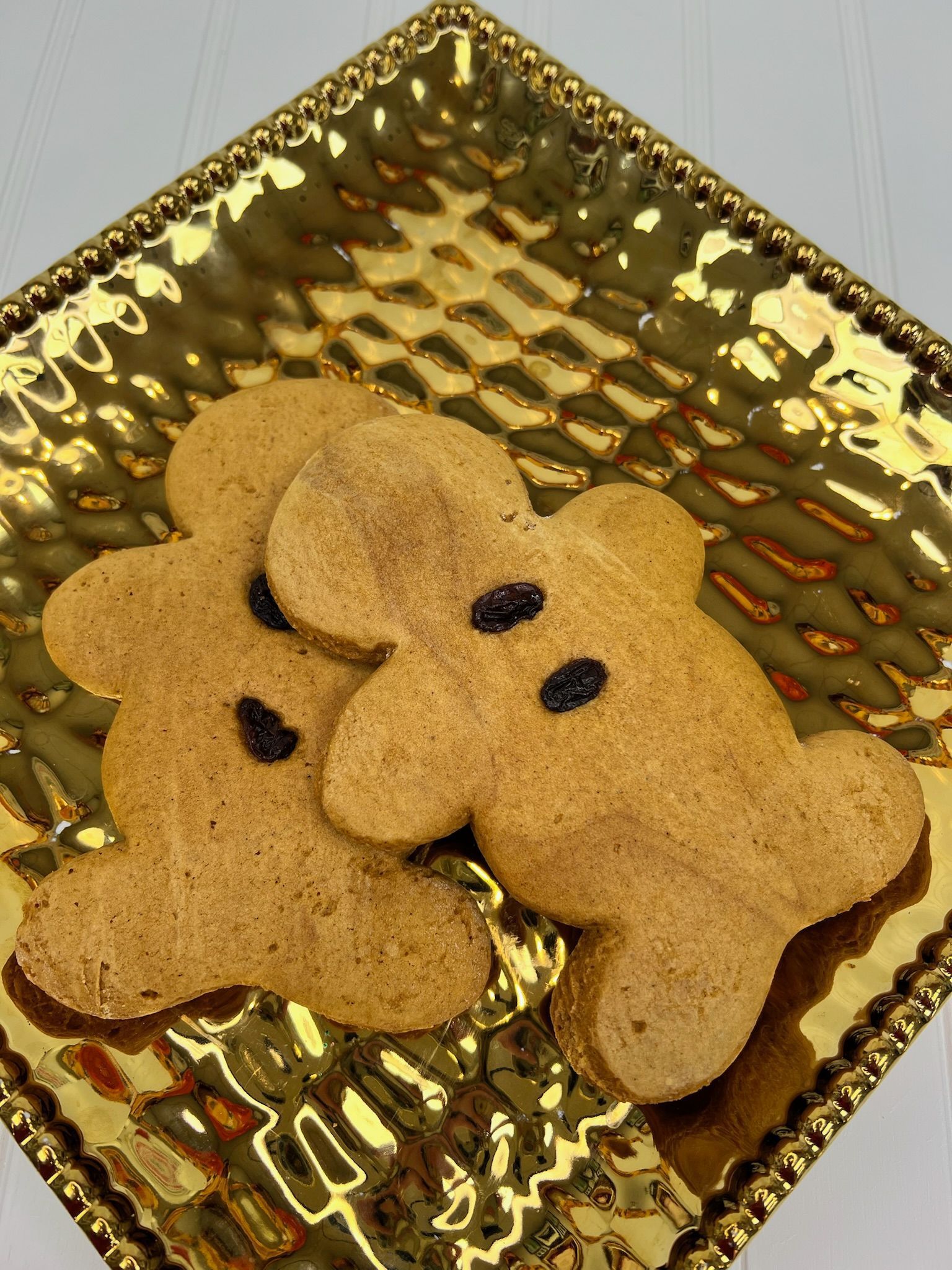 Gingerbread cookies with raisin eyes on a gold, textured platter.