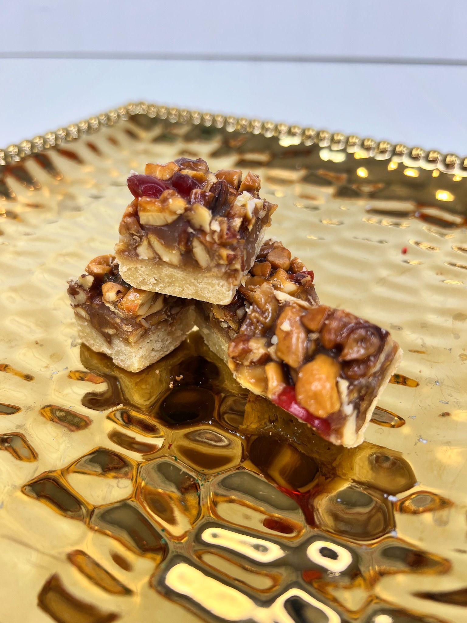 Three square dessert bars stacked on a gold textured plate.