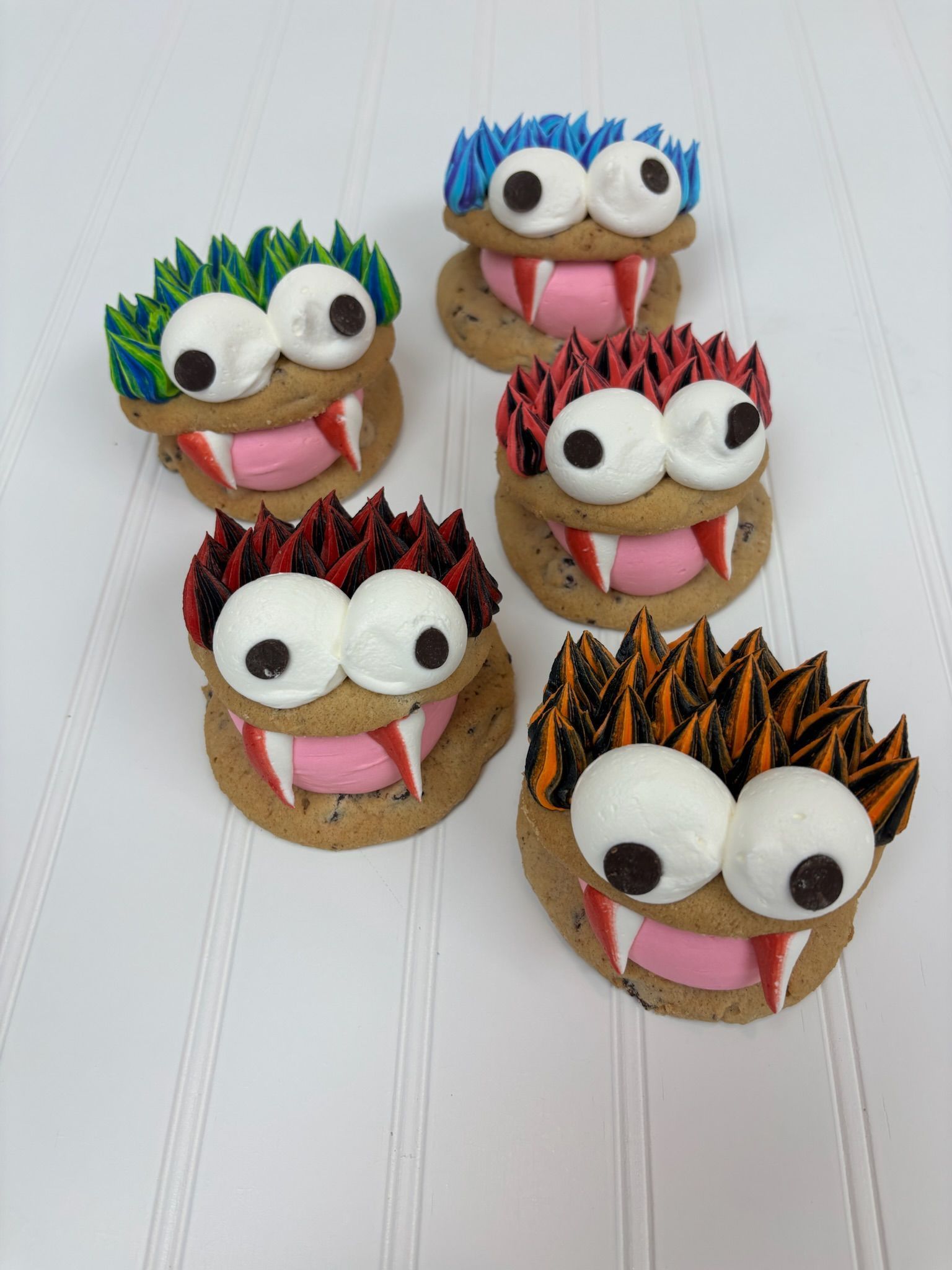 Five monster-shaped cookies with buttercream