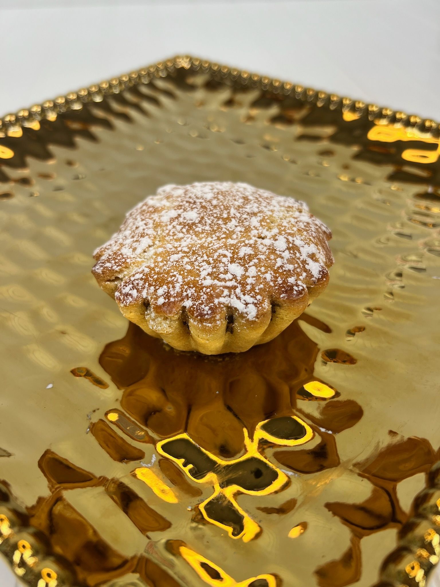 Cupcake on a decorative gold plate, dusted with powdered sugar.