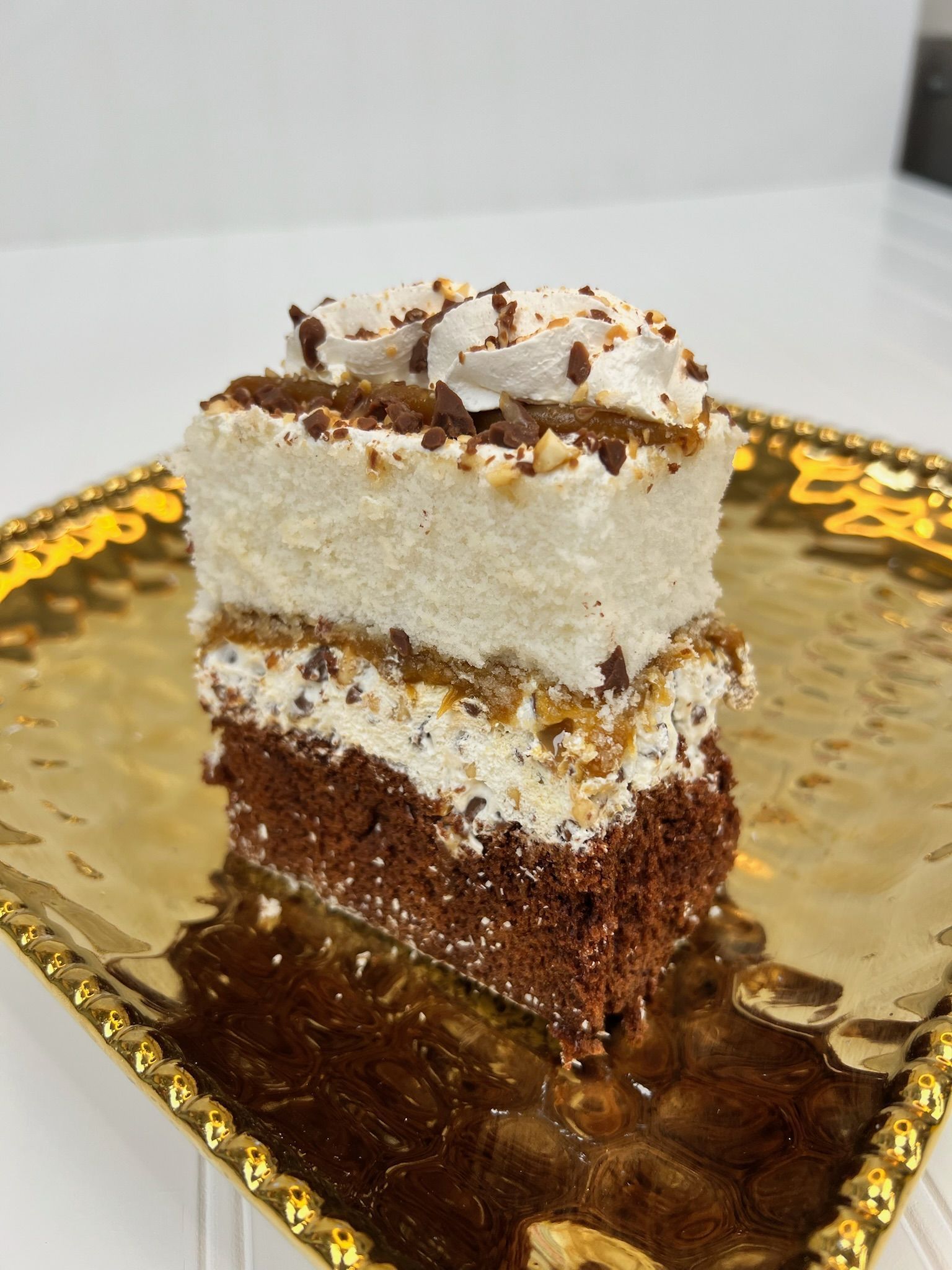 A slice of layered cake with white frosting and chocolate layers on a gold plate.
