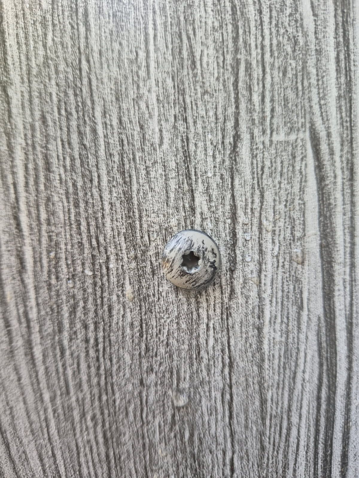 Close-up of a small hole in gray wood-grain paneling