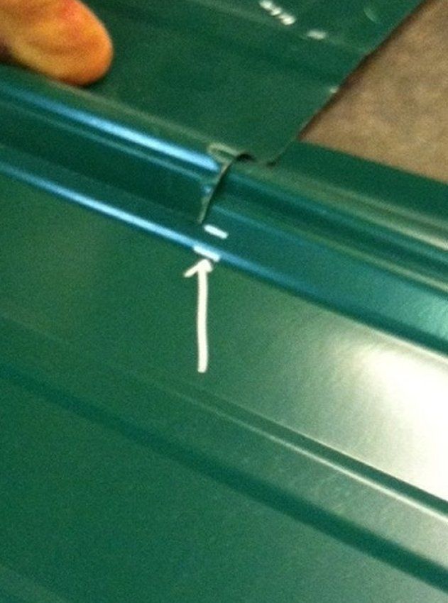 Close-up of a green plastic edge with a white arrow pointing to a small crack or seam.