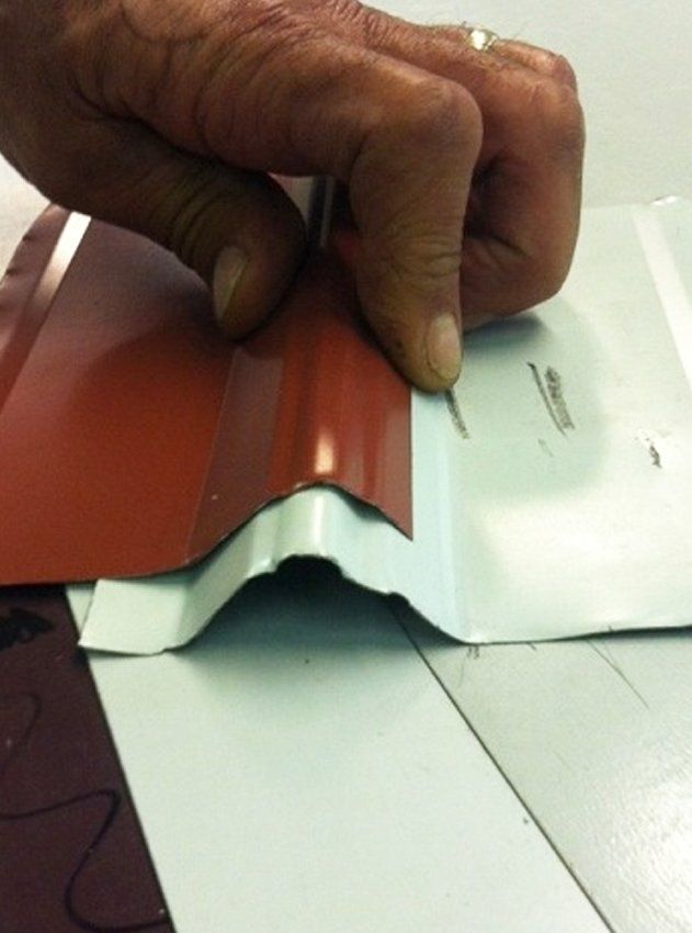 Hand pressing a red ridged sheet over a white panel seam on a table