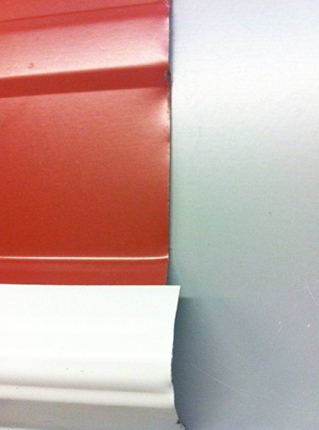 Close-up of red and white window blinds against a light gray wall.