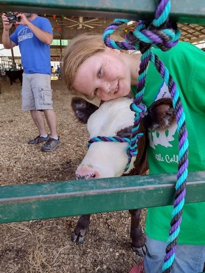 A girl in a green shirt is petting a cow