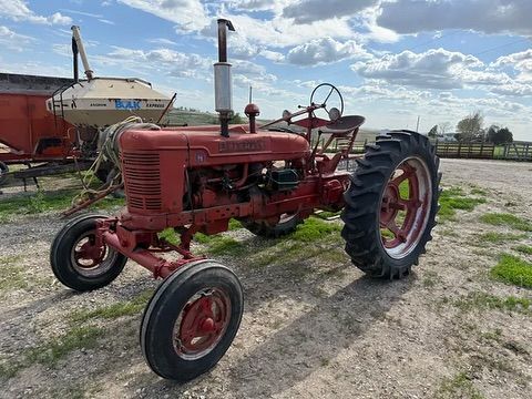 An old red tractor is parked in a dirt field.