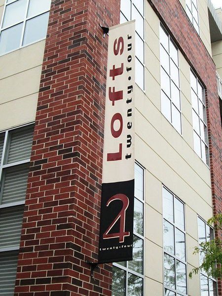 Sign for Lofts Twenty-Four on a brick building corner. Vertical banner has 