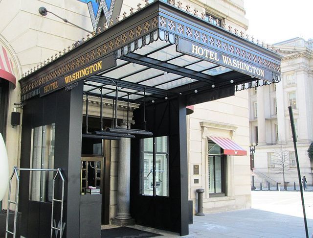 Hotel Washington entrance, black canopy with gold lettering, clear roof, and black doors.