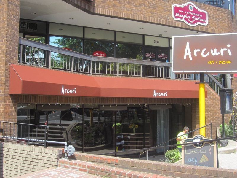 Arcuri restaurant exterior with red awning, brown sign, and glass doors.