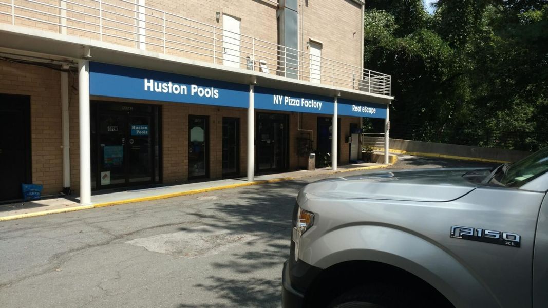 Silver pickup truck parked in front of a brick building with blue awnings that say 