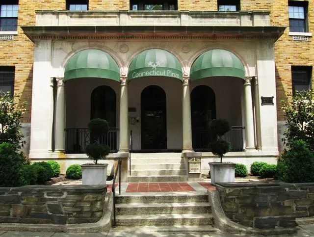 Entrance to Connecticut Place apartment building; green awnings over arched doorways, steps lead up to the entrance.