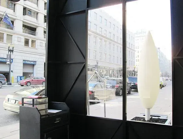 View from inside a dark-walled structure looking out onto a city street with cars and buildings.
