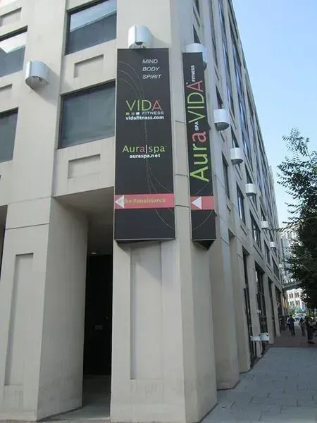 Exterior of a building with signs for Vida Fitness and Aura-Vida spa. Vertical black signs on a corner entrance.