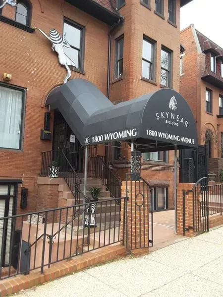 Exterior of Skywear Interiors building, brick facade, black awning over entrance, metal railing.