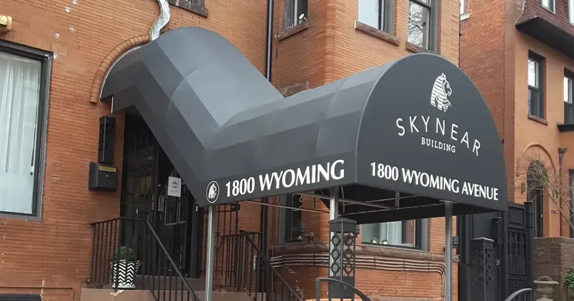 Black awning over a brick building entrance; reads 