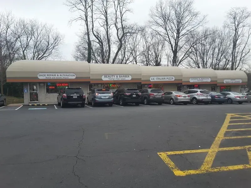 Strip mall with businesses, cars parked out front, overcast sky.